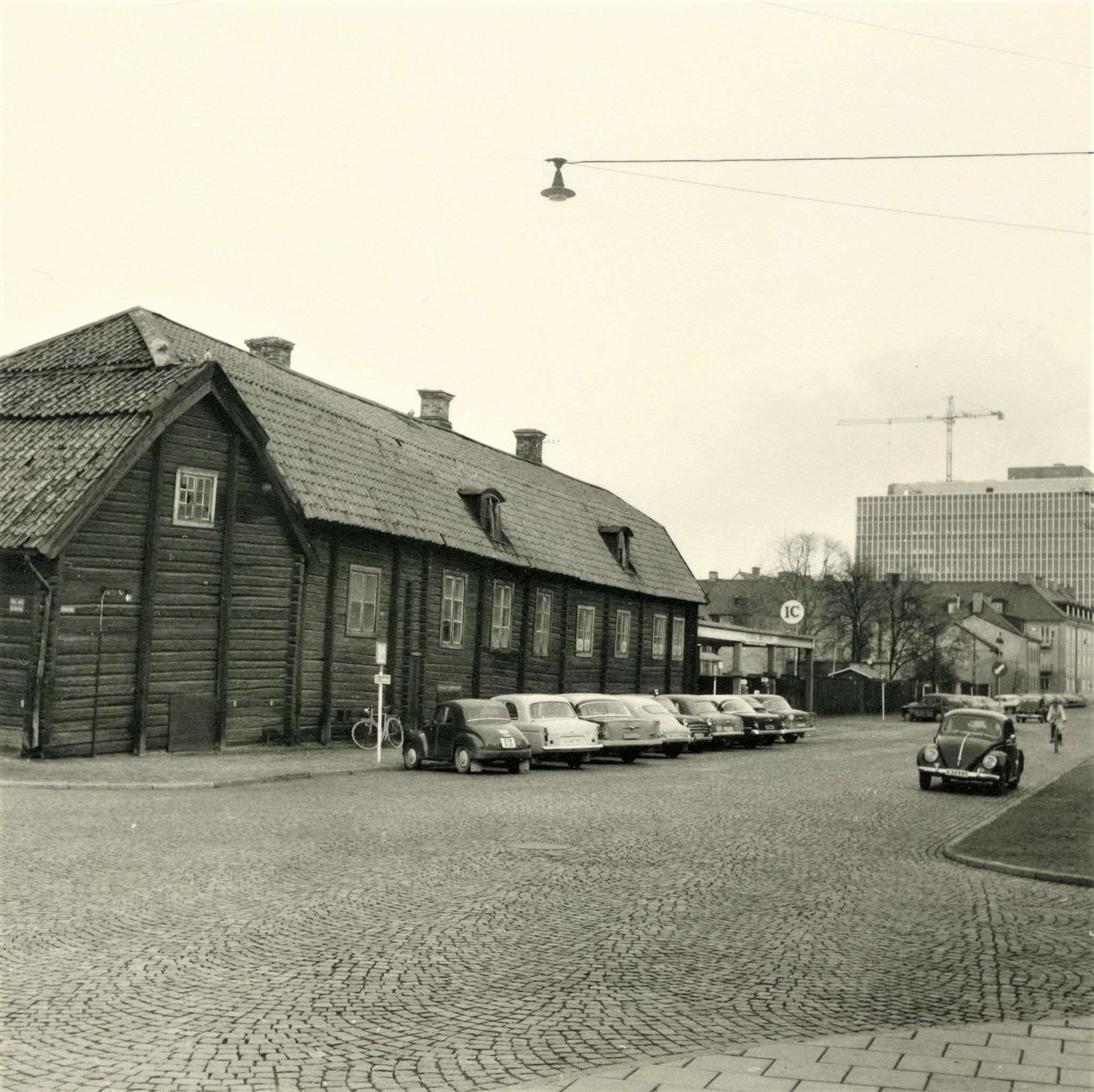 En rad med parkerade bilar framför ett trähus.