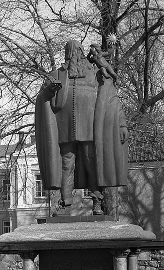 Staty av Johannes Rudbeckius med en bok i högra handen och ett litet barn på vänstra axeln.