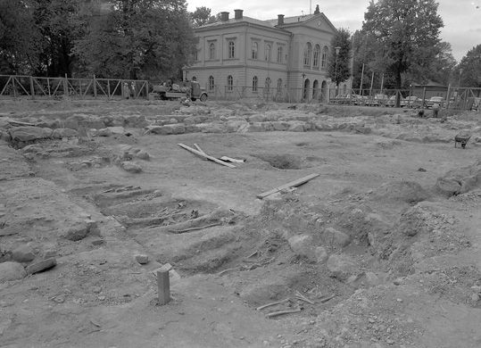 Ett utgrävt torg med flera skelett i gravar.