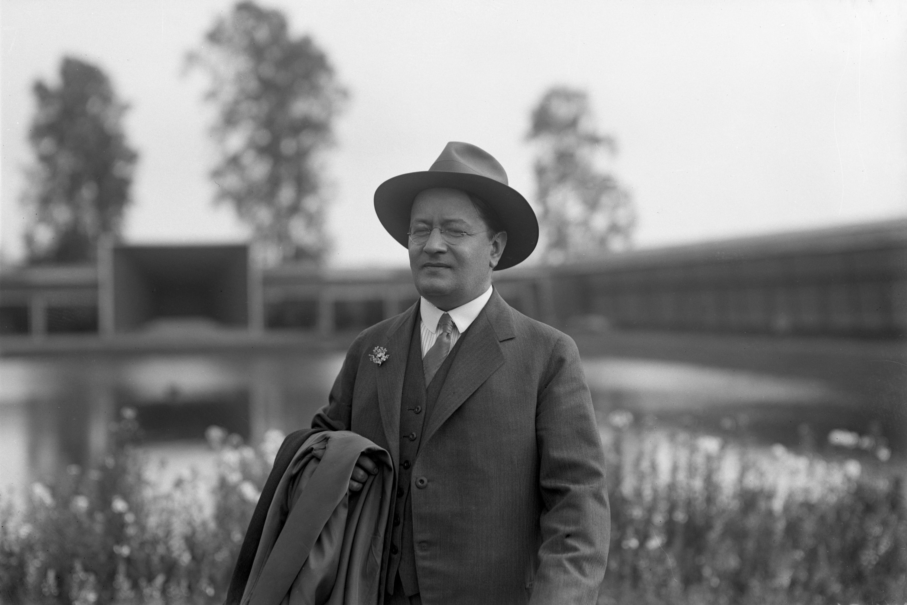 Cyrillus Johansson iklädd hatt och kavaj med Värmlands museum i bakgrunden.