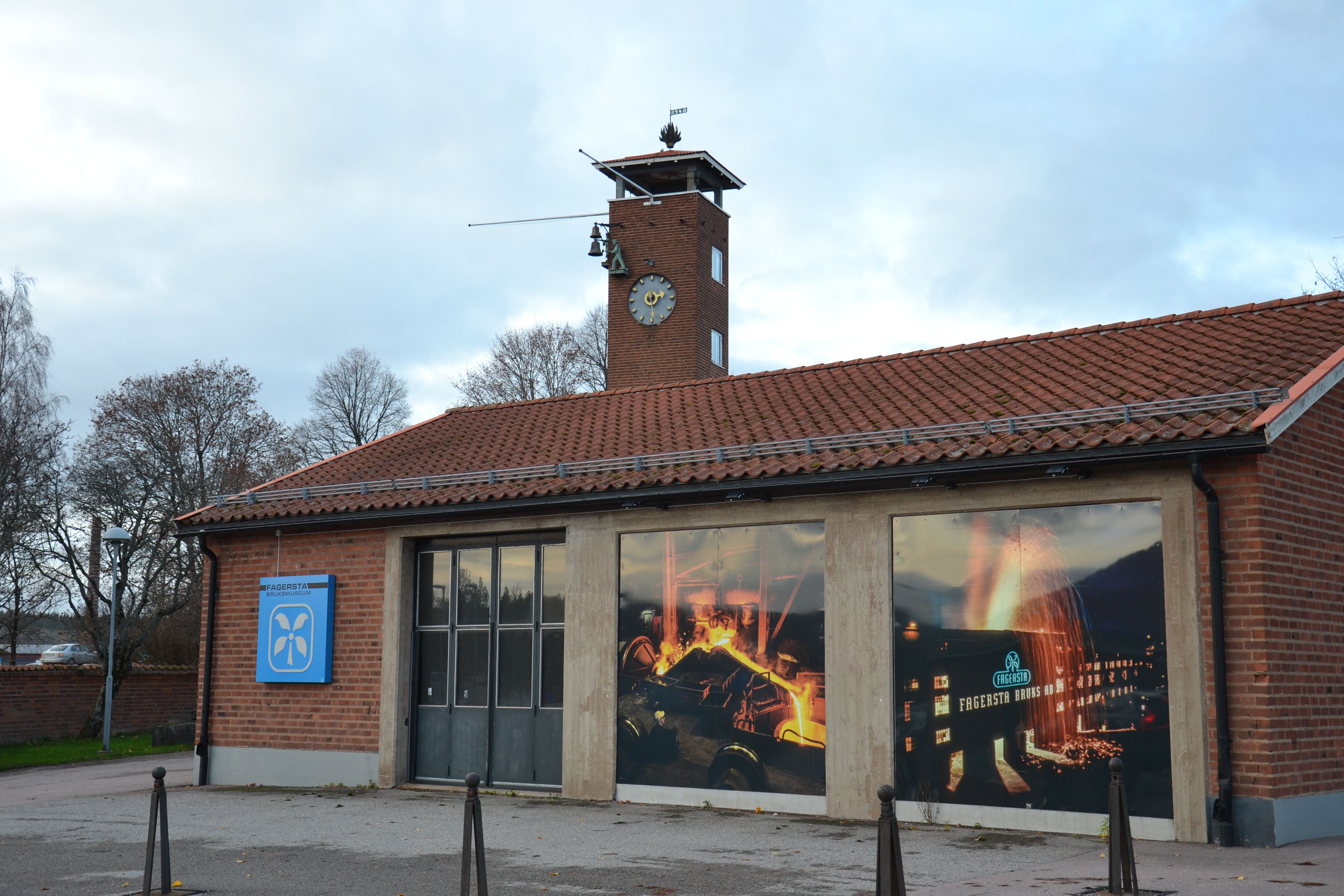 Bilden visar den gamla brandstationen i Fagersta. Där finns bruksmuseet sedan 1993. På framsidan finns en port för brandbilar och två som är helt igenlagda med stora färgbilder från Fagersta bruk.