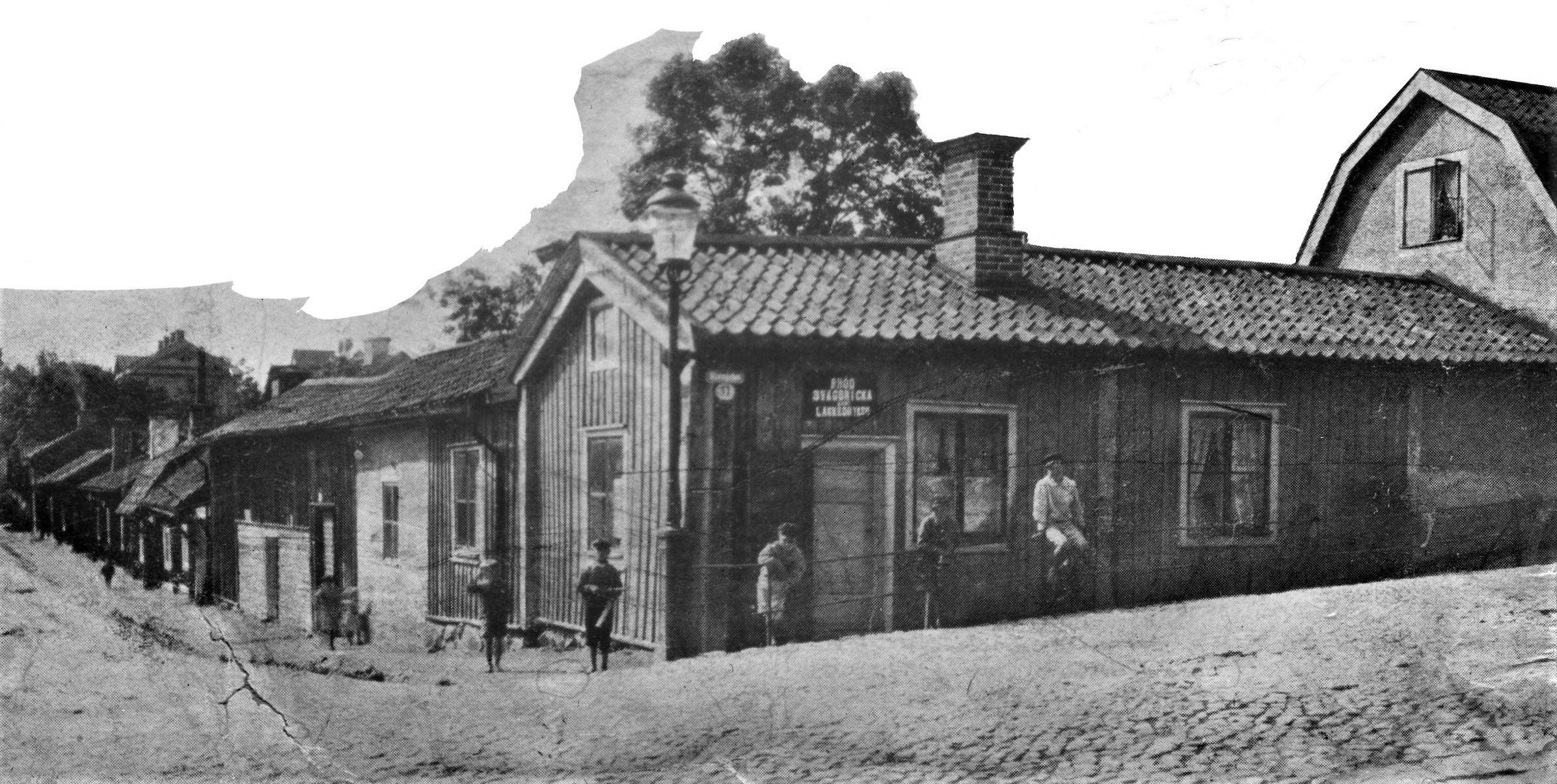 Ett trähus i ett gatuhörn. Några barn står utanför.
