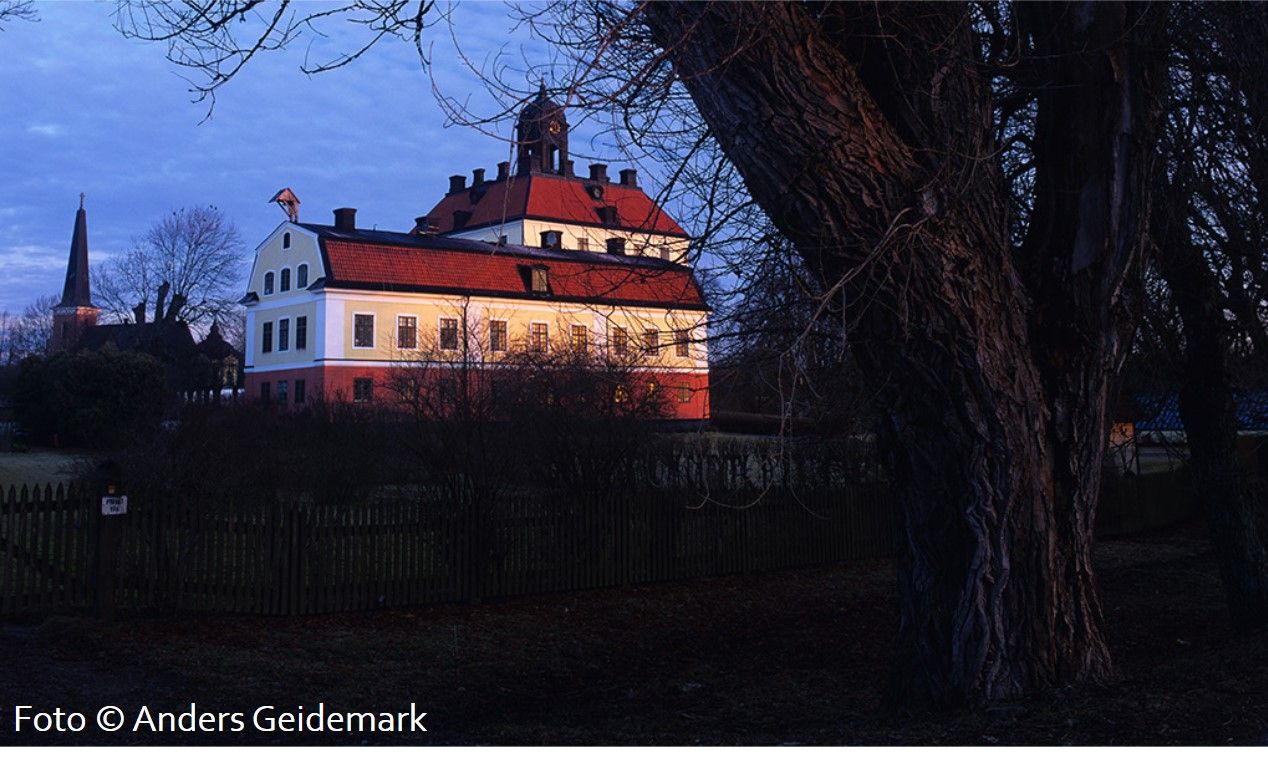 En slottsbyggnad och ett kyrktorn längre bort.