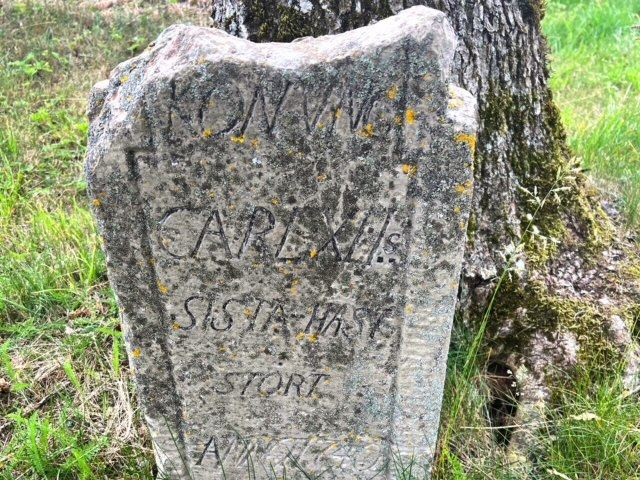 Bilden visar en gravsten med grovhuggen text: Konung Carl XII:s sista häst stört(ade och dog) anno 1740.