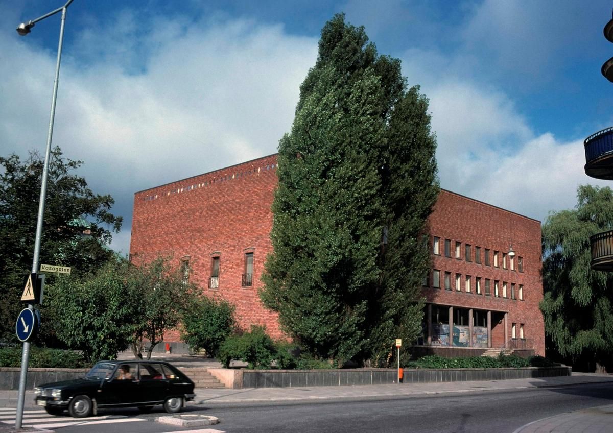 En postmodernistisk röd tegelbyggnad med gatuvy i förgrunden.