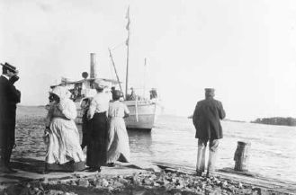 Svartvit foto visandes ett ångfartyg som angör vid en brygga
