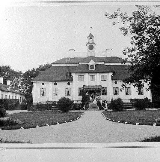 En ljus herrgårdsbyggnad framifrån