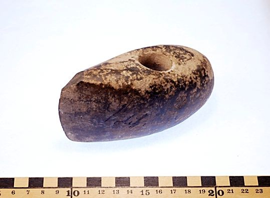 Yxa av sten med borrat skafthål och polerad yta.